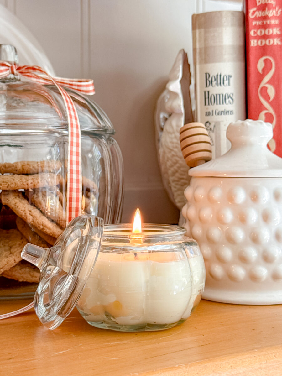 Homemade beeswax candle in a small jar lite next to other decorations