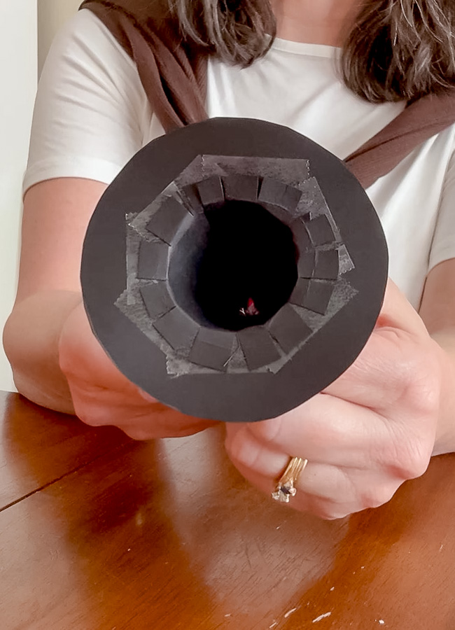 Taping down the slit paper to make a tiny witch hat