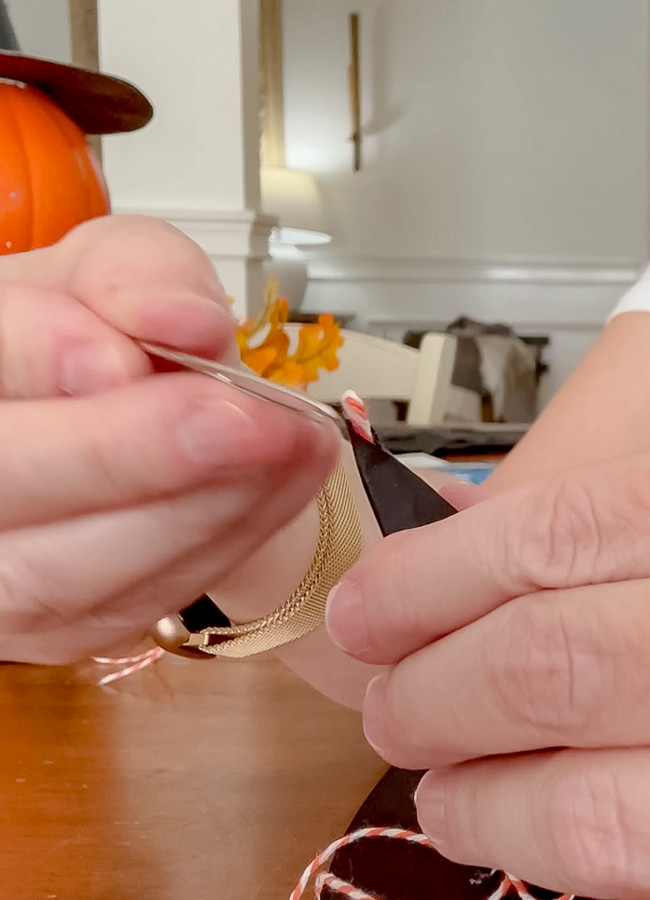 Threading twine through the top of the paper witch hat to create a loop for hanging the garland.
