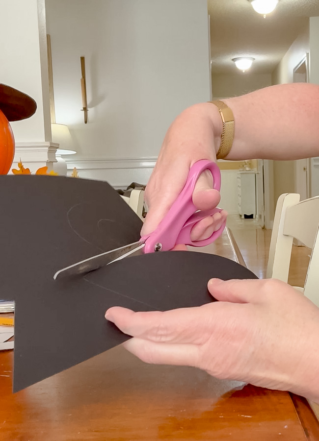 Cutting out paper witch hat pieces using a printable witch hat template on black cardstock.