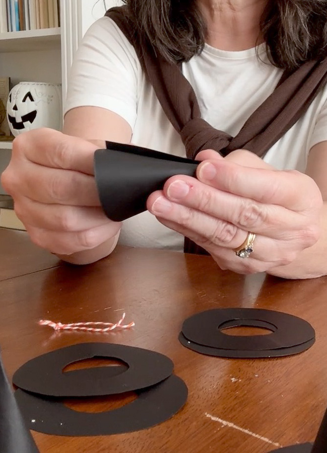 Rolling the paper into a cone shape to create the top of the mini paper witch hat.