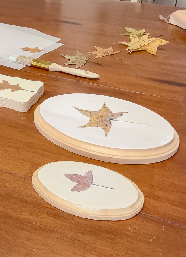 Painting preserved leaves onto a piece of painted wood to preserve it.