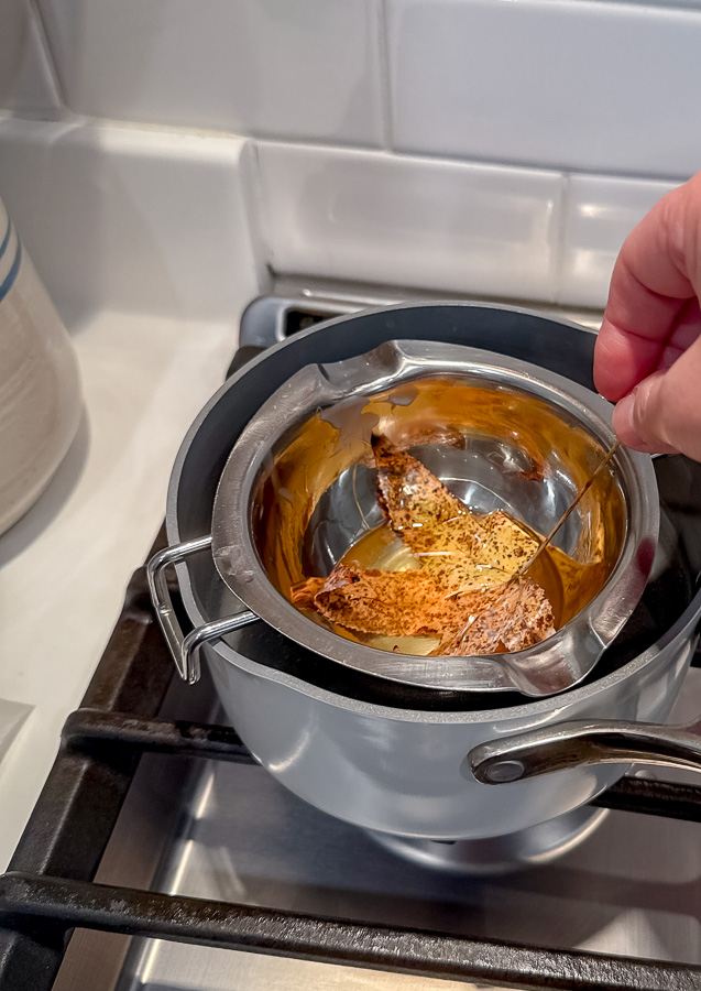 Dipping a leaf in melted beeswax.