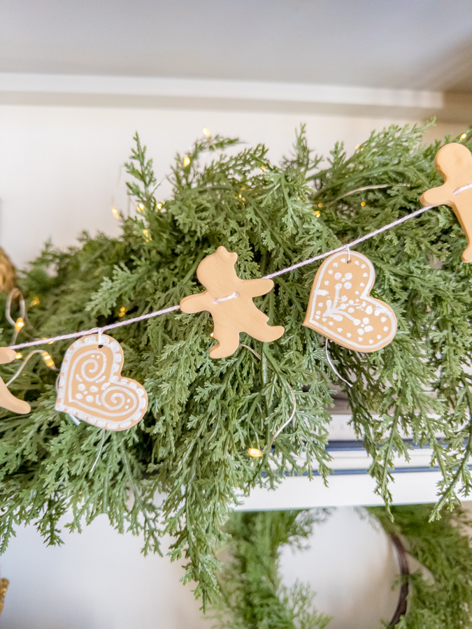 Air dry clay gingerbread garland hanging in front of greenery