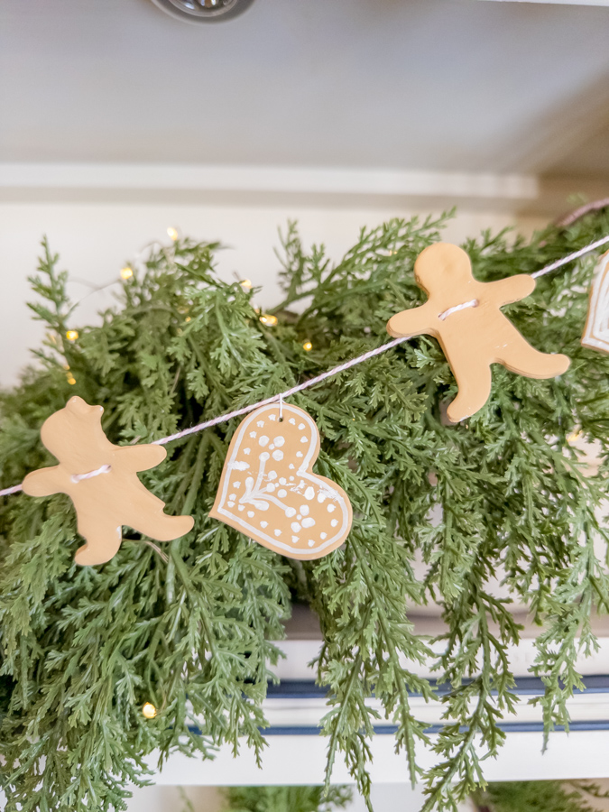 Ginger bread garland hanging in front of Christmas greenery