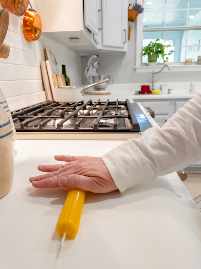 Rolling the end of a beeswax sheet to form a taper candle.