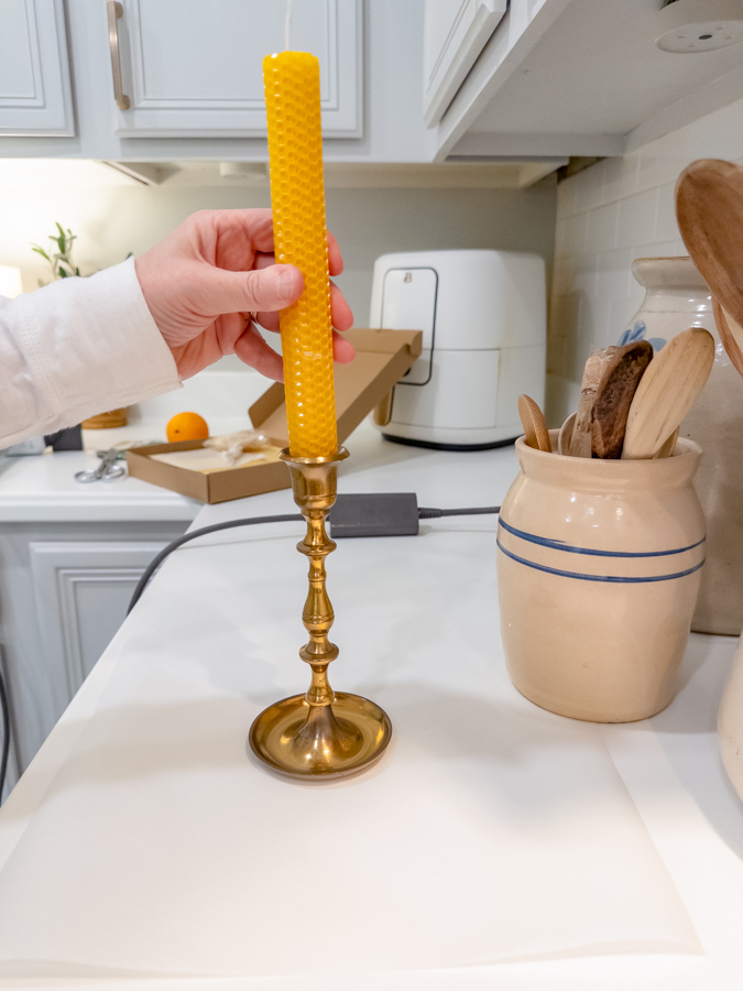 Place a rolled beeswax candle that has been heated on the bottom to fit into a brass candle holder