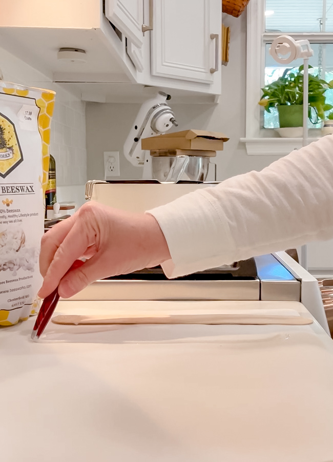 Place homemade candle wick on parchment paper with tweezers