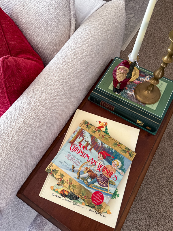 Dark wood end table with Christmas decorations, brass candlestick holders and vintage books.