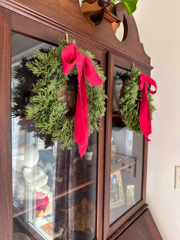 Secretary with two small Christmas wreaths with red bows