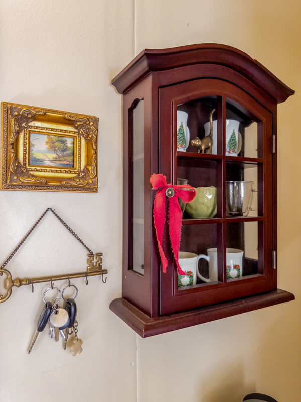 Curio cabinet on a wall with vintage Christmas mugs