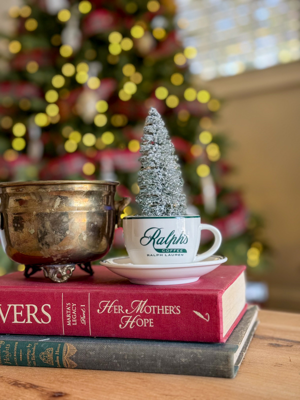 Ralph's coffee mug by Ralph Lauren and bottome brush tree Christmas decorations inside sitting on a stack of vintage books