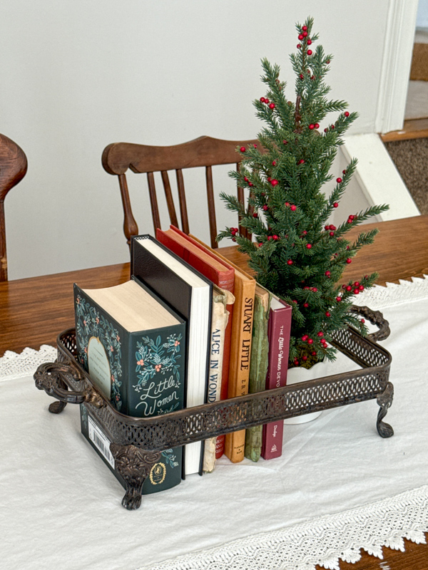 Vintage Christmas centerpiece idea with small tree with red berries, vintage books and a vintage silver holder for pyrex dish