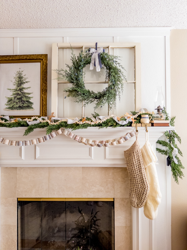 Fireplace mantel decorated with Little House elements. Old window, lots of greenery, ticking fabric ribbon, gingerbread men cookies, paper chain, knit stocking, oil lamp, crock pots, old books and botanical tree art.