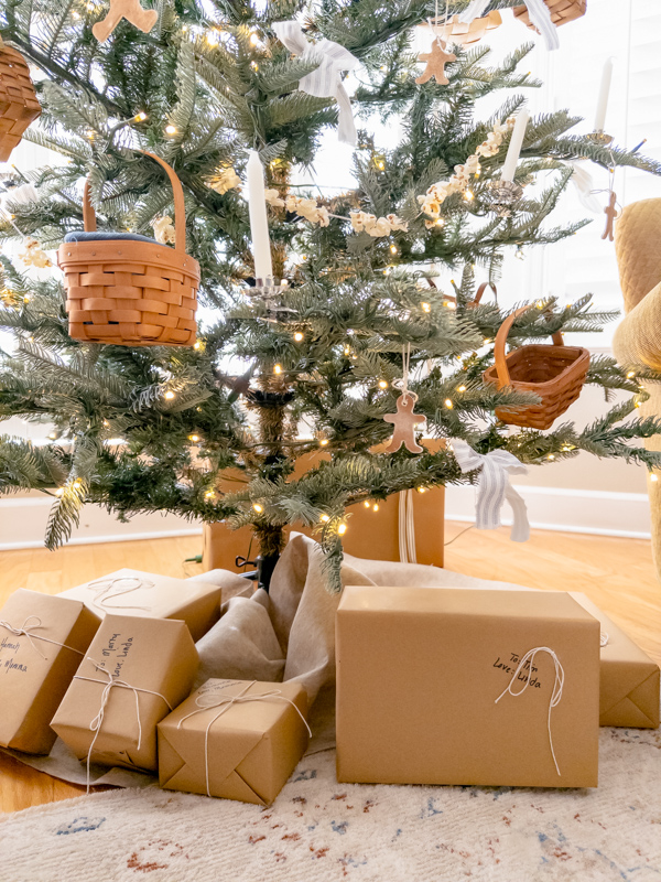 Little House on the Prairie style Christmas tree with baskets, candles, gingerbread cookies made of air dry clay, popcorn garland and presents wrapped in brown paper and tied with string