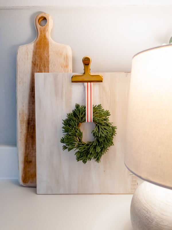 Homemade cutting board with mini wreath attached with red and white ribbon.