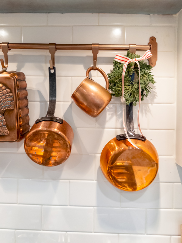 Copper pans hangin over stove with mini wreath with red and white ribbon bow