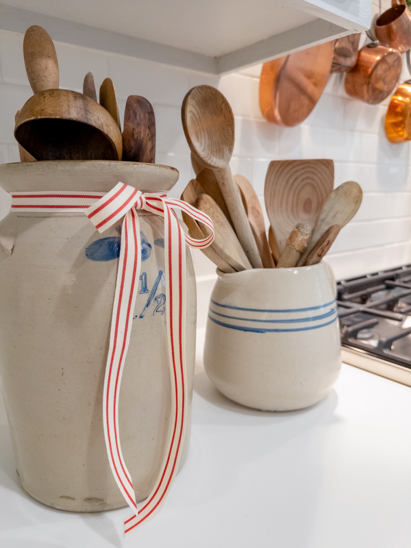 Kitchen Christmas decorations with old crocks tied with red and white ribbons and filled with old wooden spoons