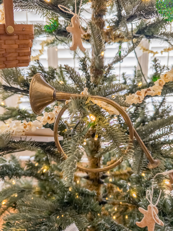 Prairie style Christmas tree decorated with popcorn garland, gingerbread men cookeis and vintage brass french horn.