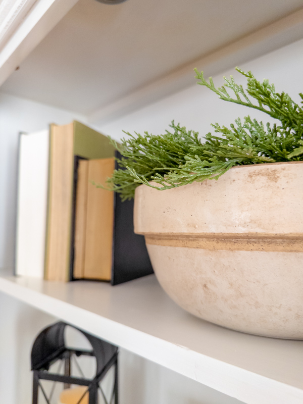Crock bowl with greenery next to old books.