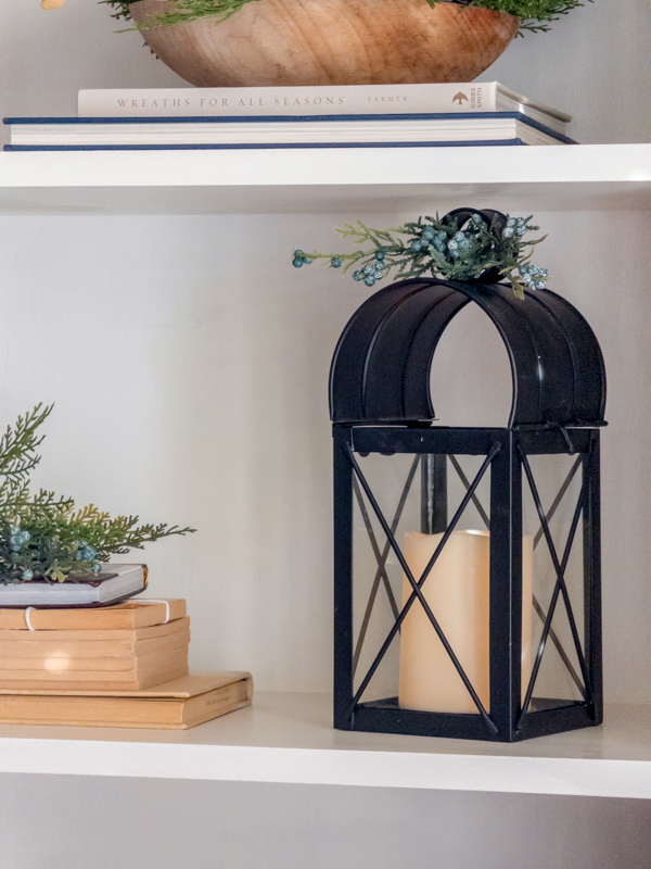 Black lantern with Christmas greenery and old books.