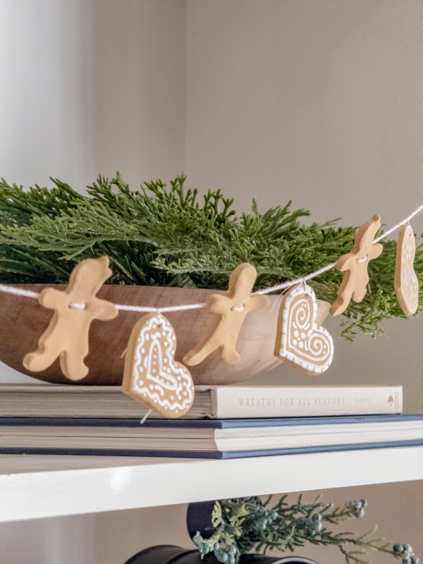 DIY air dry clay gingerbread heart, man and woman garland hanging on a bookcase