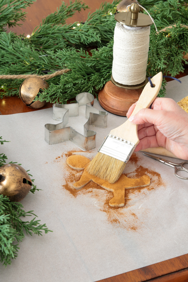 Brushing cinnamon onto a air dry clay gingerbread man ornament
