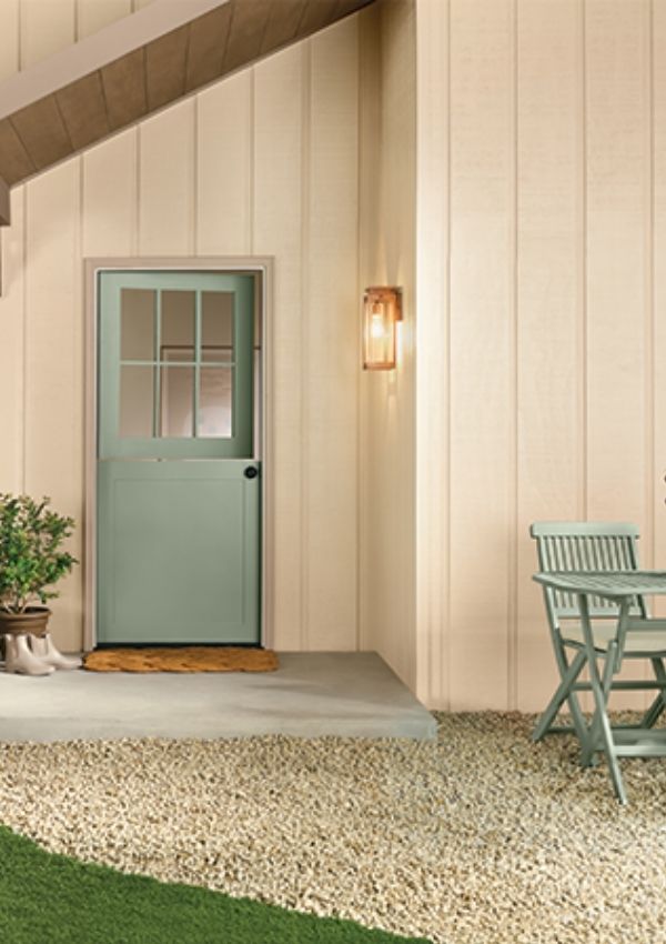 Exterior of a house painted in Melodious Ivory by Dutch Boy. A muted light yellow color.