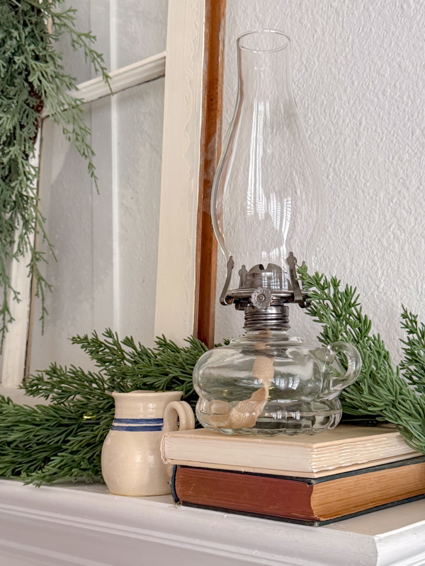 Chamber lamp sitting on a stack of old books and a small mini creamer crock