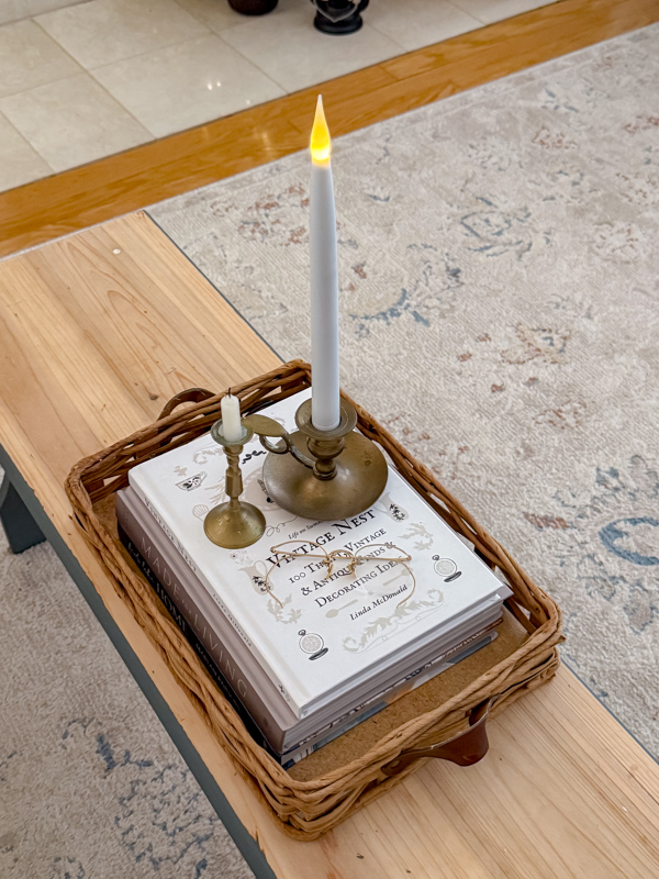January Home Decor Ideas using candles on a stack of books sitting in a basket tray on a coffee table.