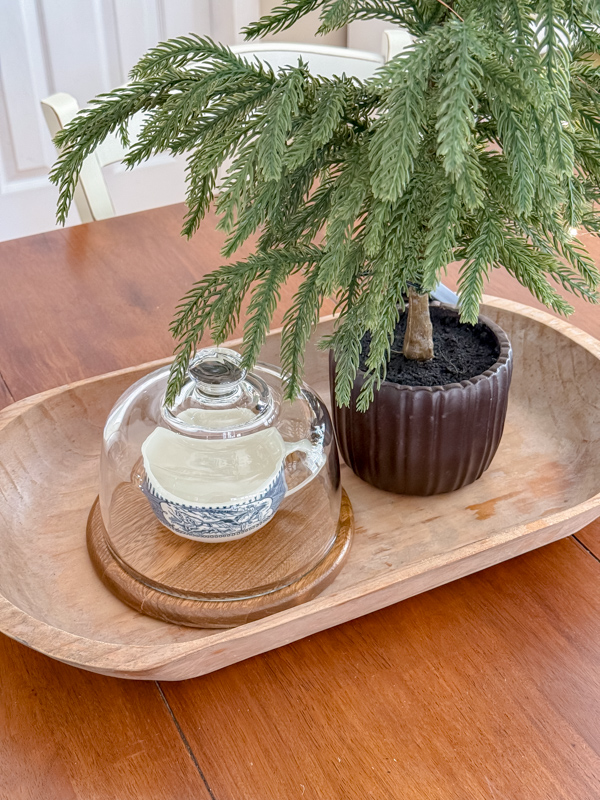 Library table centerpiece for winter. Wood dough bowl tray, small tree, cloche with a Currier & Ives teacup inside