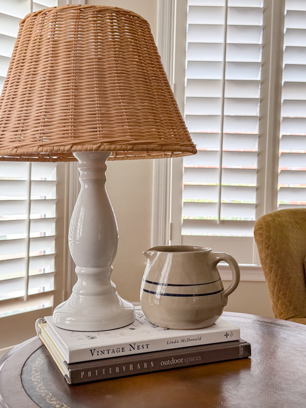 Winter vintage decor ideas. White lamp with basket shade and crock milk pitcher sitting on a stack of books.