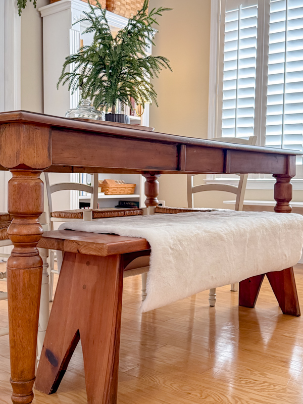 Sheepskin rug draped over a bench to add a cozy, soft and warm touch to your dining table.