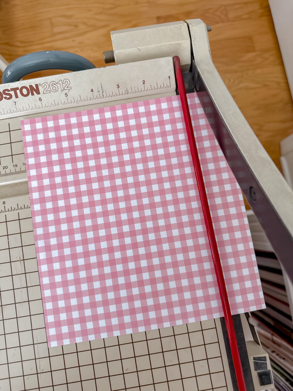 Cutting pink and white check paper on a cutting board