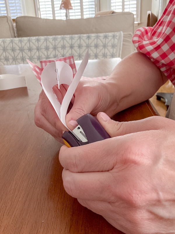 Stapling hearts together to make a heart paper chain.