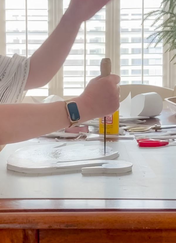 Putting a hole in a swan printable with an ice pic that has foam board behind it.