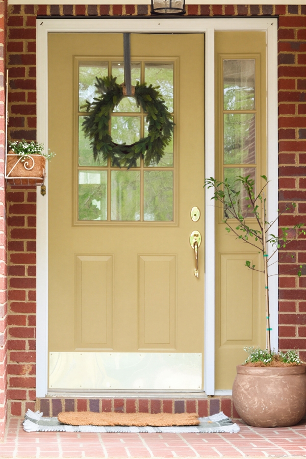 Yellow front door painted Peace Yellow by Sherwin Williams on brick home