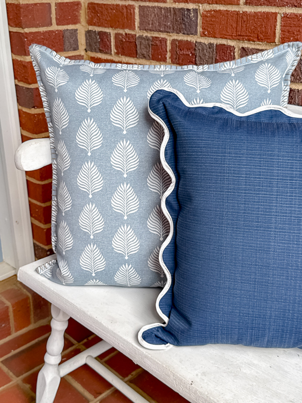 White vintage bench styled with allen + roth blue and white outdoor pillows from Lowe's for a spring porch refresh.