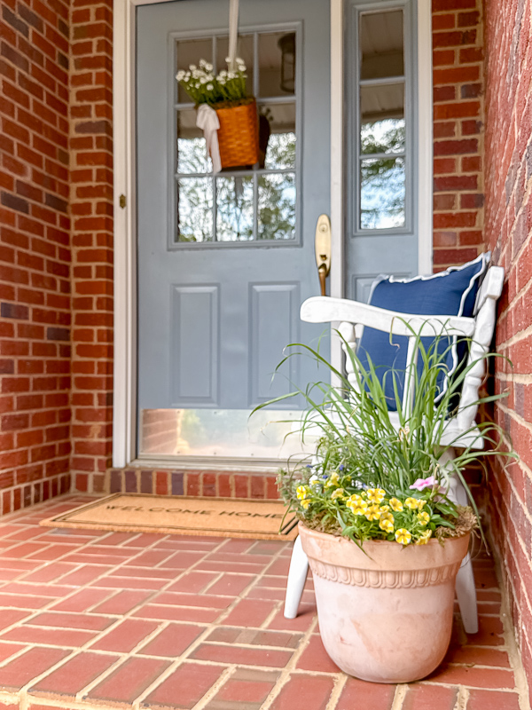 Full front porch reveal featuring a white vintage bench, terracotta container gardens, and spring door basket decor after a 15-minute spring cleaning.