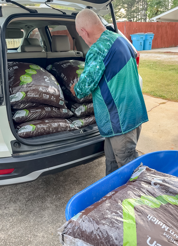 Unloading bags of mulch onto a wheel barrel.