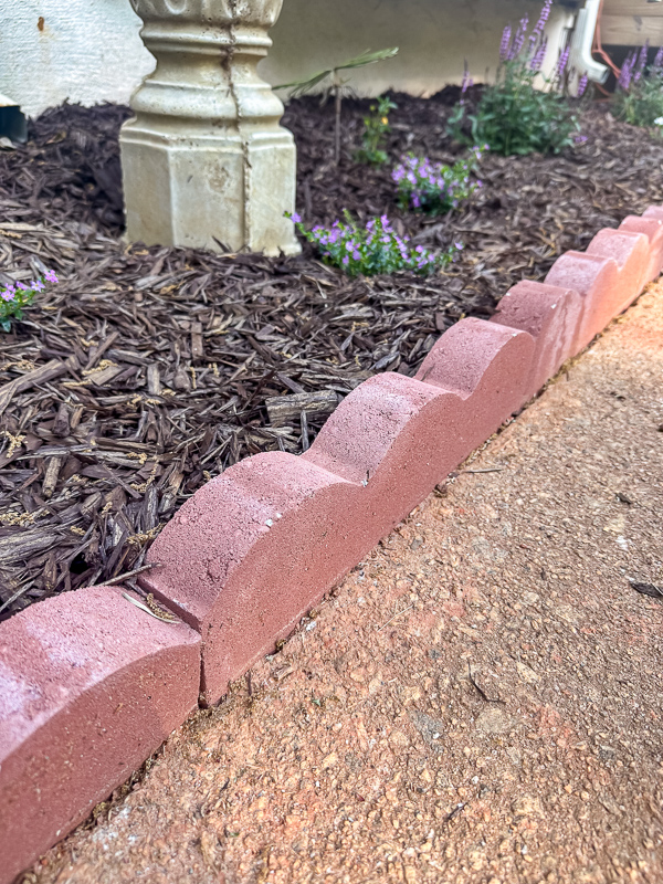Scallop brick edge border between a sidewalk and flower bed.
