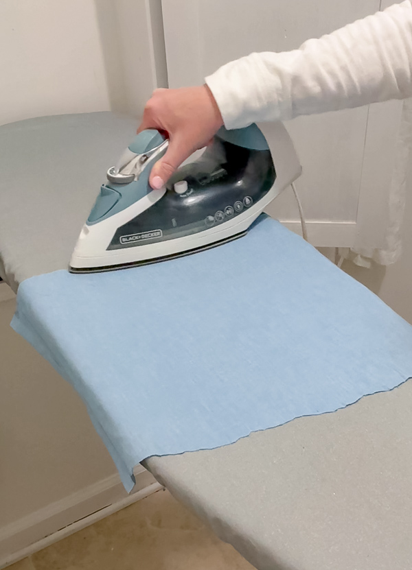 Ironing chambray fabric flat with a steam iron before applying it to peel and stick foam board for DIY framed American flag art