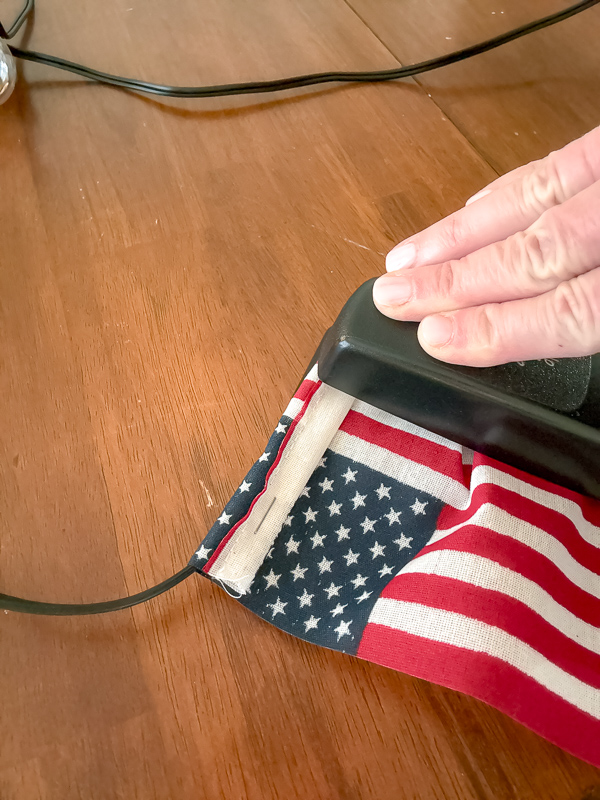 Stapling an American flag to solar string light wire to make a DIY American flag string light garland