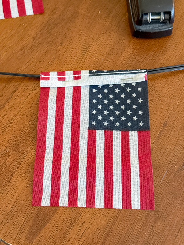 American flag stapled between two string light bulbs for a homemade patriotic garland decoration