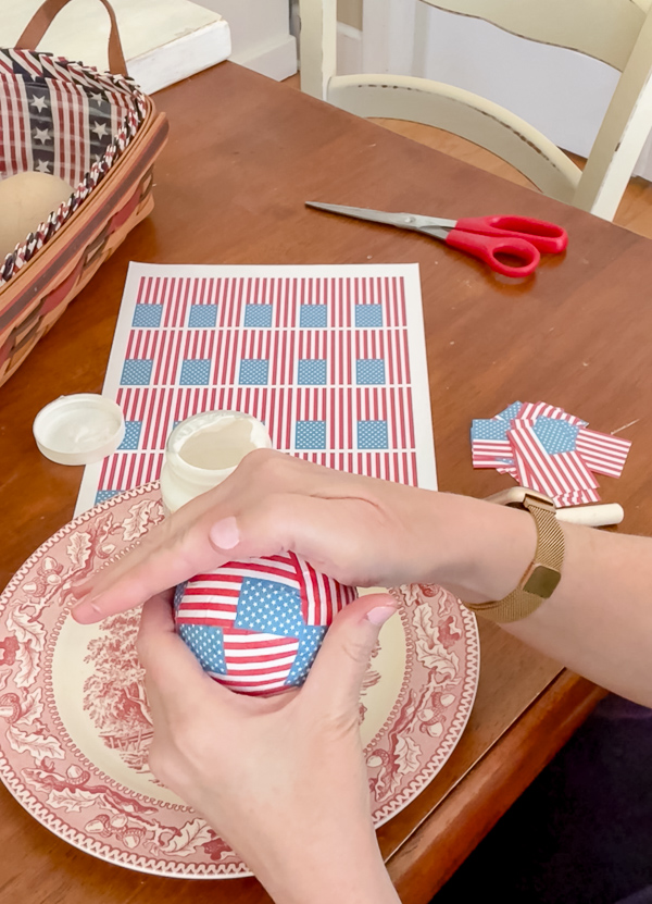 Adding paper mini American flags to a ball.