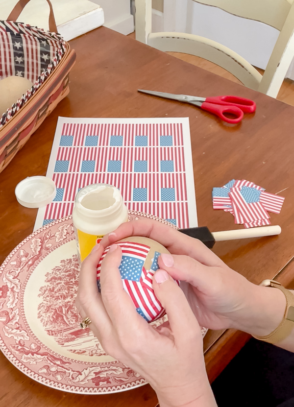 Applying small American flags to a paper mache ball.