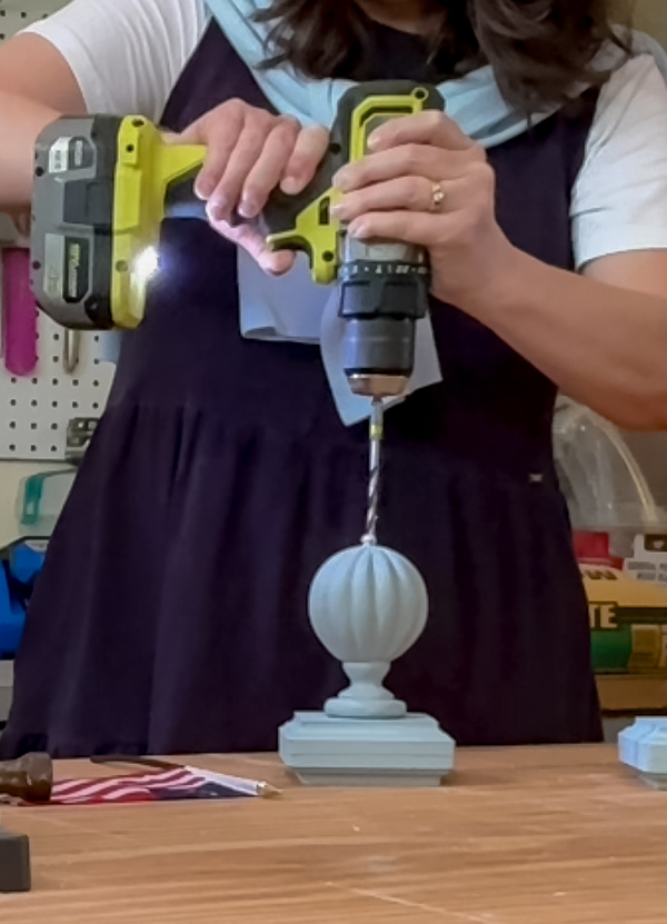 Drilling a hole in the top of a painted wood finial with a Ryobi drill to make a DIY patriotic finial flag stand for 4th of July home decor