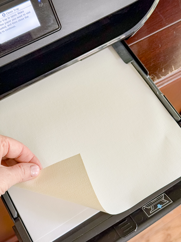Inkjet canvas paper loaded in a home printer with one end turned over to show printing on the whitest side for best results