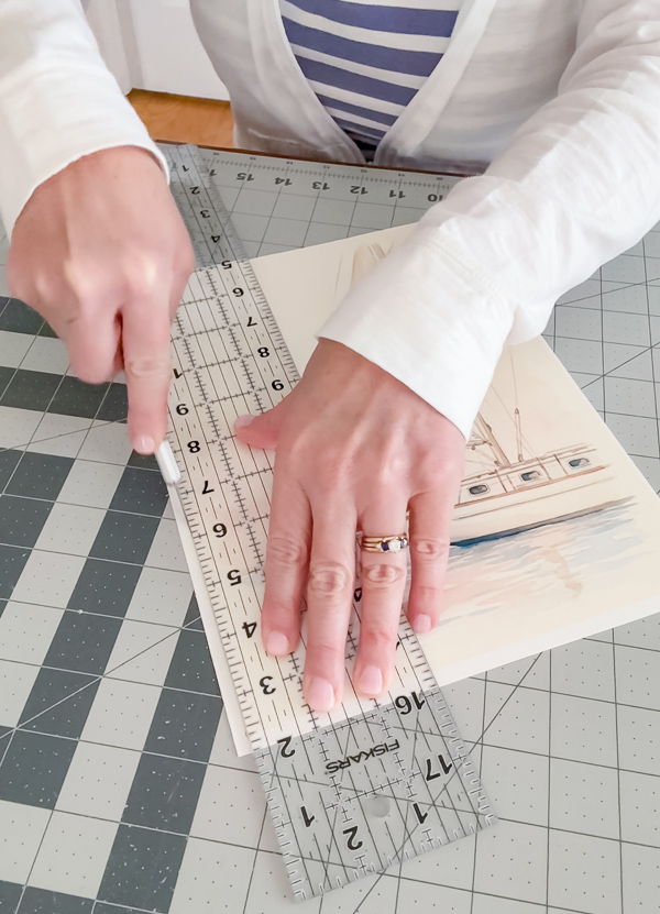 Using an X-ACTO knife, clear ruler, and cutting mat to trim the white border off a sailboat printed on inkjet canvas paper at home