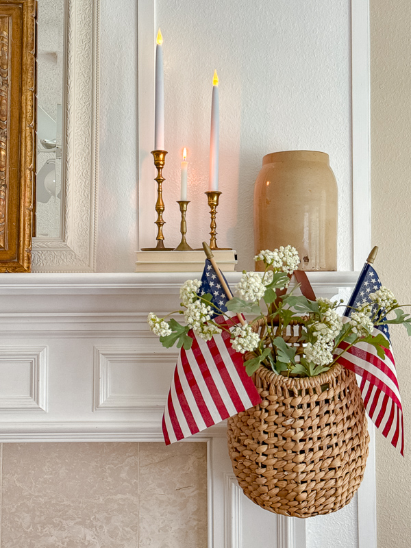 Ralph Lauren Americana mantel styling with brass candlesticks, white taper candles, and a woven wall basket with American flags and white blooms